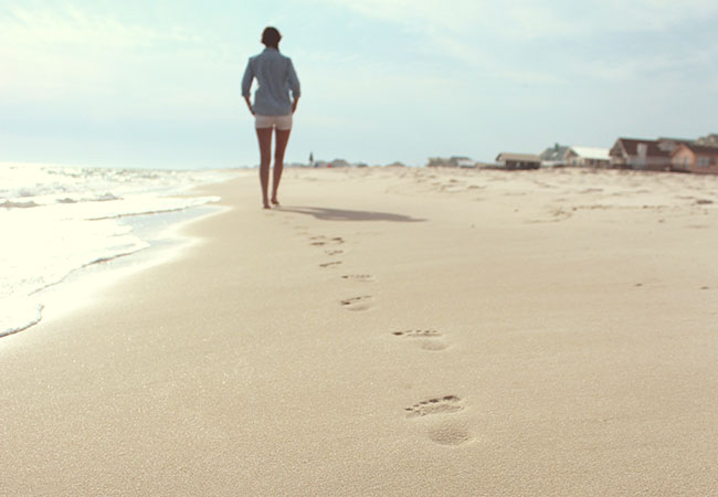 Zu sehen ist ein Strand mit einer Person von hinten; sie hat Fußspuren im Sand hinterlassen. Spuren hinterlassen auch Internetnutzer. Das ist der Digitale Nachlass. Bild: unsplash/@zackography